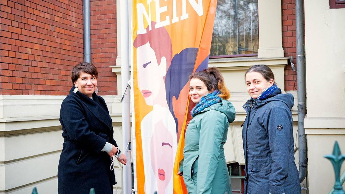 Katharina Slanina, Claudia Sprengel und Julia Wiedemann stehen neben der UN-Women-Flagge, die an einem Fahnenmast besfestigt ist